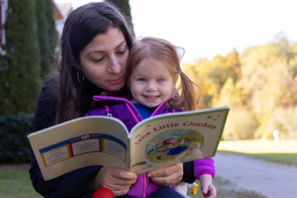 mother reading to small child outside on a sunny fall day