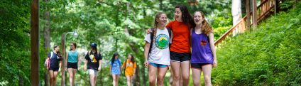 Group of three campers walking with their arms around their shoulders.