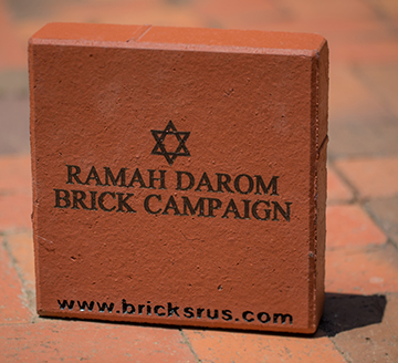Commemorative brick sample. Red square brick with black writing.