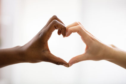 Close Up Of Multiracial Female Friend's Hands Showing Heart Shape Against White Background