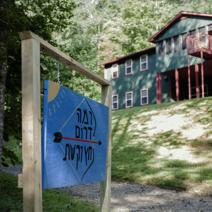 Picture of the Ramah Darom archery range sign with a cabin in the background