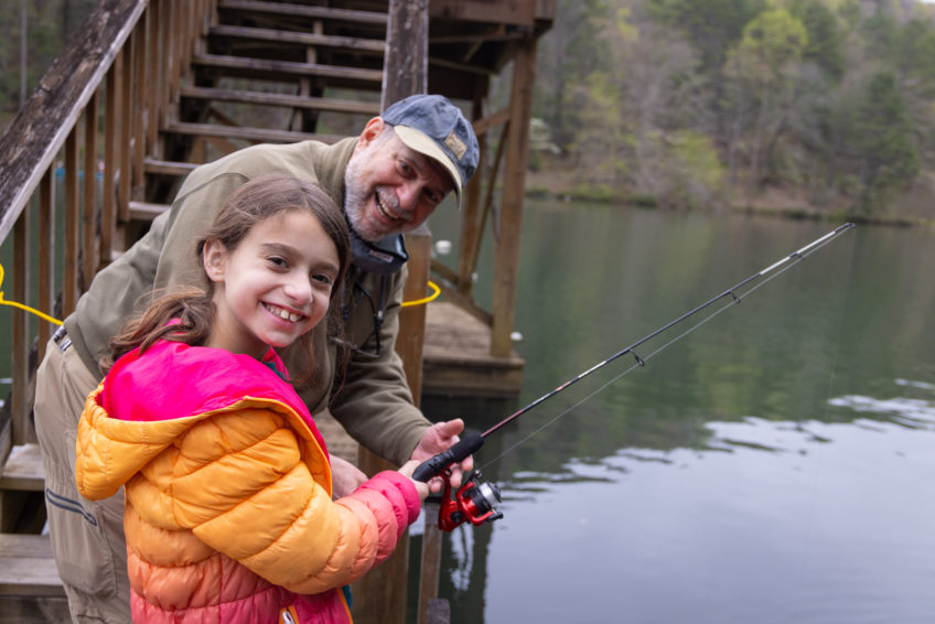 8 year old girl and grandfather smiling while fishing