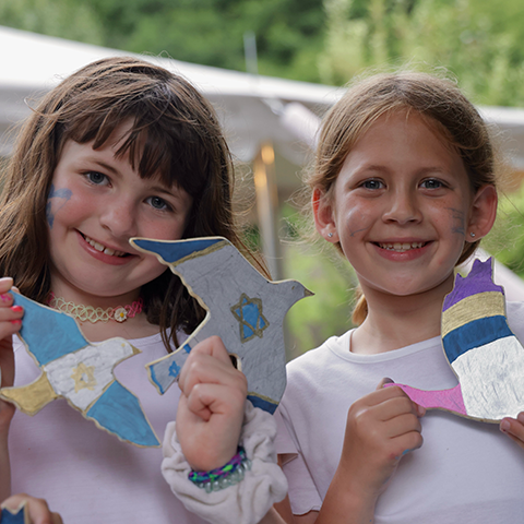 two young girl campers smiling showing off their artwork