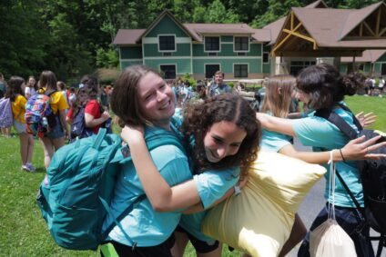 Campers hugging with pillows, backpack and huge smiles